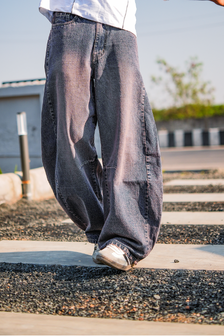 Person wearing a white shirt and gray pants walking on a street.